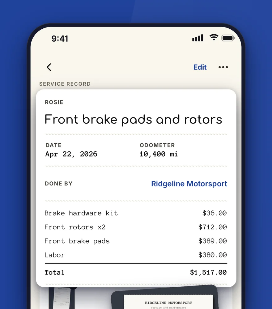 A service record for front brake pads and rotors with each part and its price, lifted out, and the paper invoice beside it.